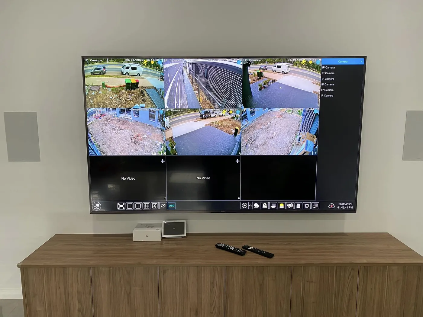 Six security camera feeds on a wall-mounted TV above a timber cabinet