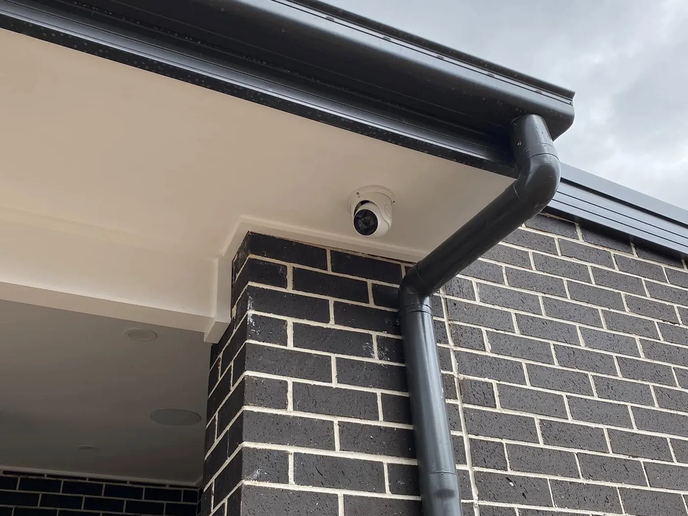 Dome security camera under the eaves of a brick home