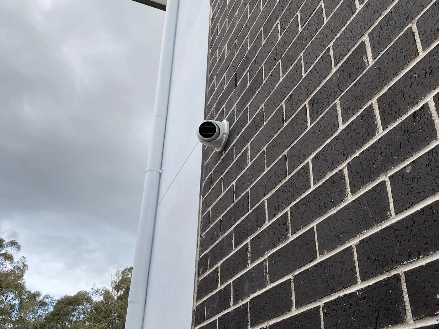 Dome security camera on a dark brick wall