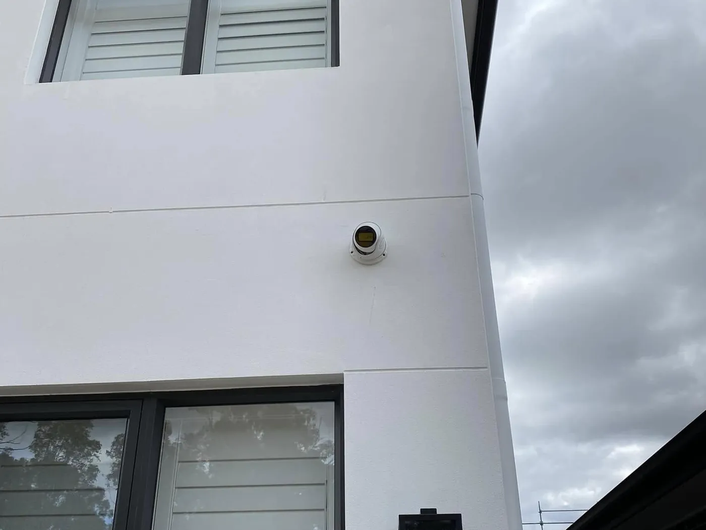 Dome security camera on a rendered wall between two windows