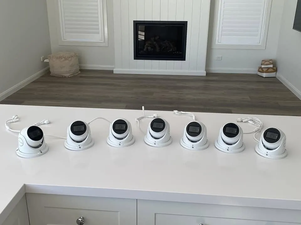 Seven dome security cameras lined up on a benchtop before installation