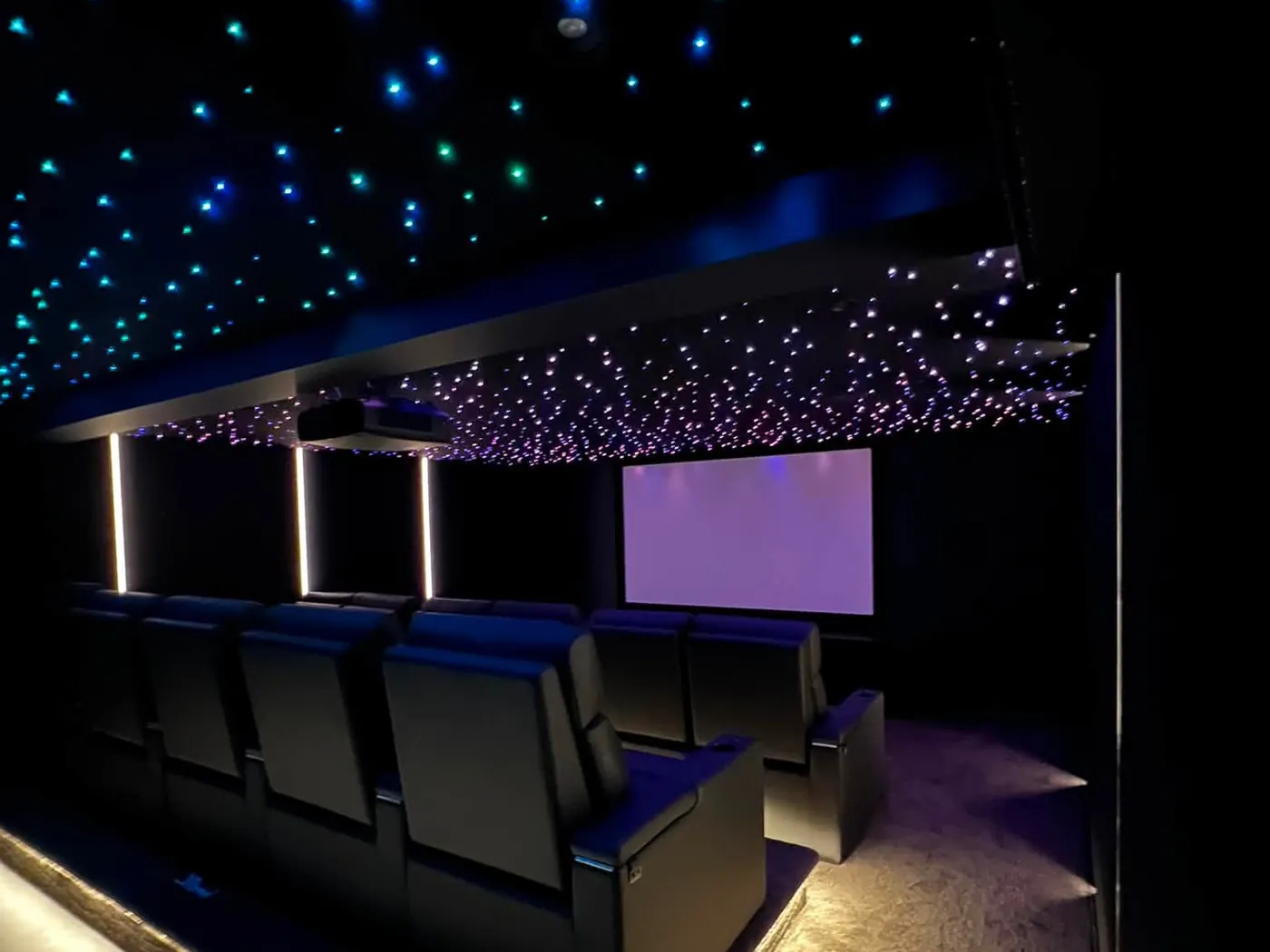 Finished cinema room with a star-light ceiling and recliners on a raised platform