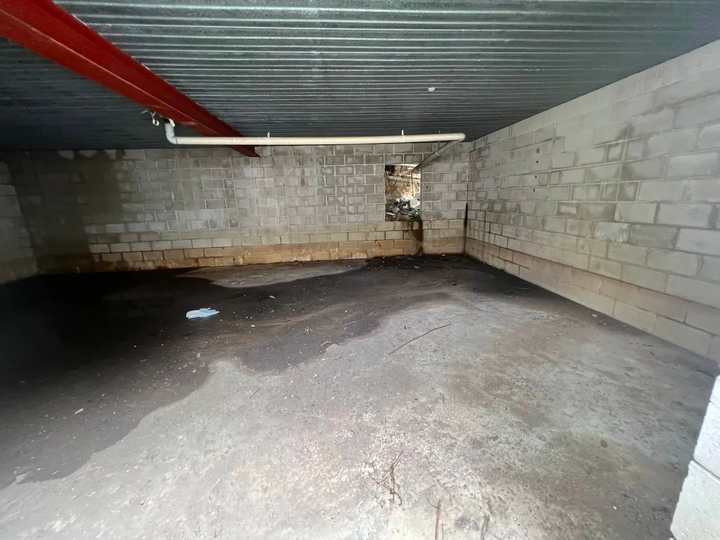 Raw under-house space with block walls and a dirt floor, before the build