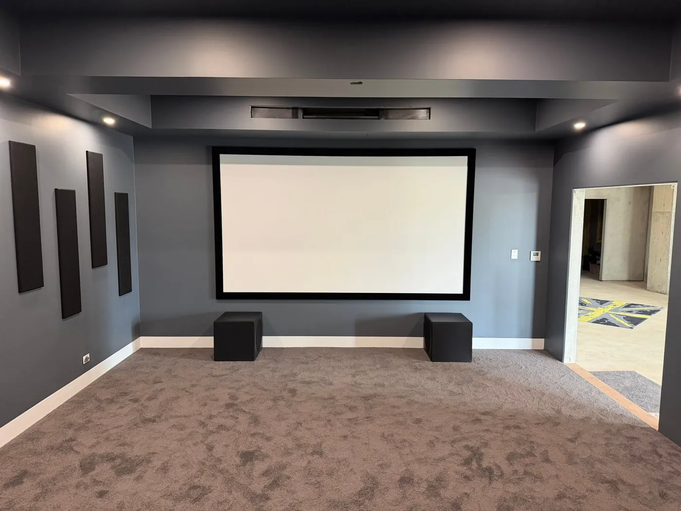 Finished cinema room with a large projection screen, acoustic panels and new carpet