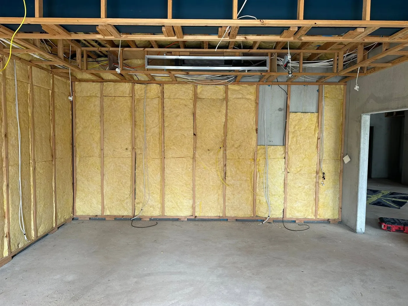 Framed-out room with insulation and exposed ceiling joists, before the build