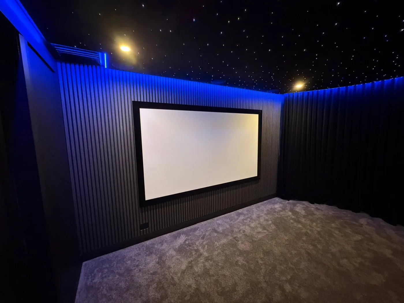 Finished cinema room with slatted walls, a star-light ceiling and blue LED lighting