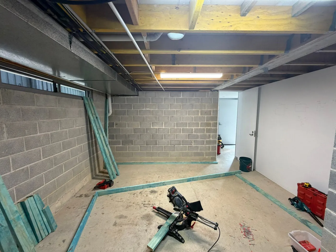 Basement room mid-build with block walls, exposed joists and timber framing