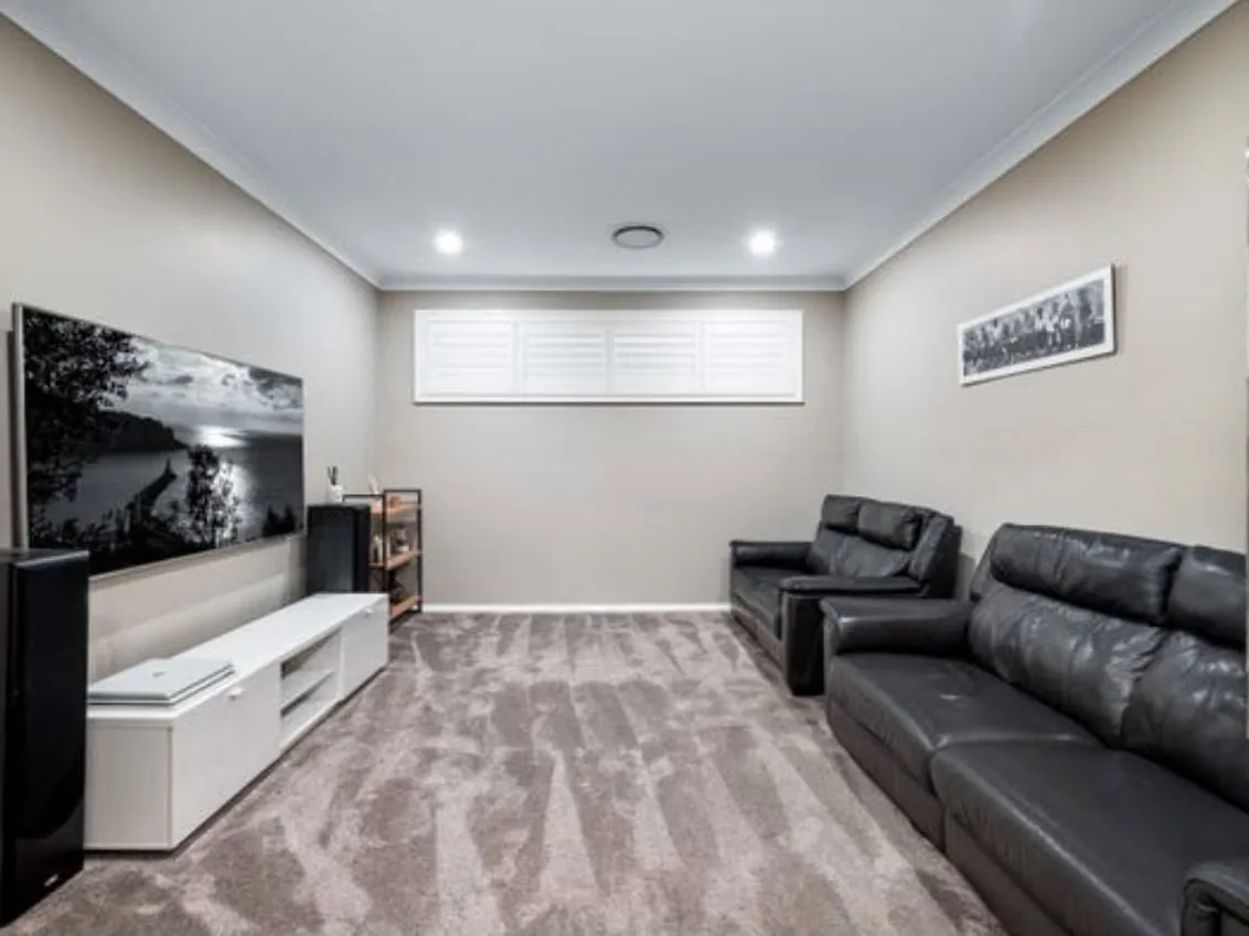 Lounge room with a wall-mounted TV and leather sofas, before the build