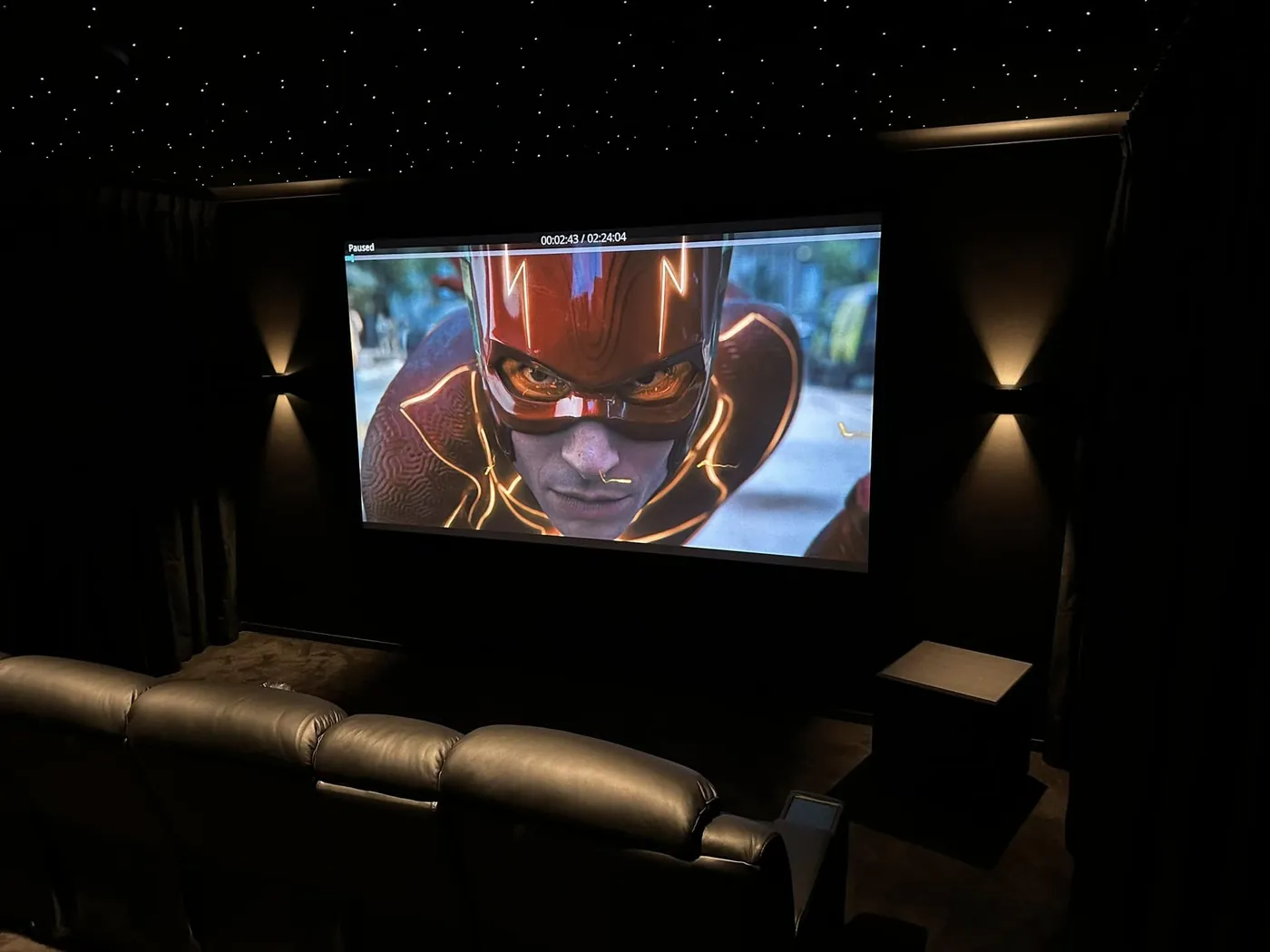 Wall sconces either side of a projection screen with recliners in front