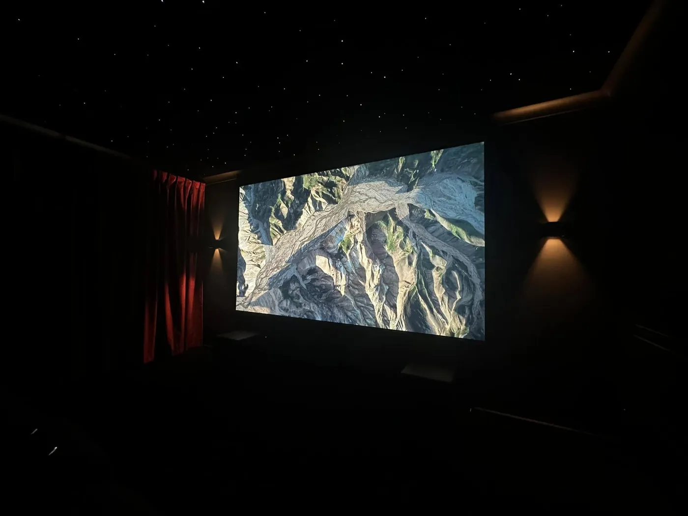 Wall sconces lighting the curtains beside a projection screen
