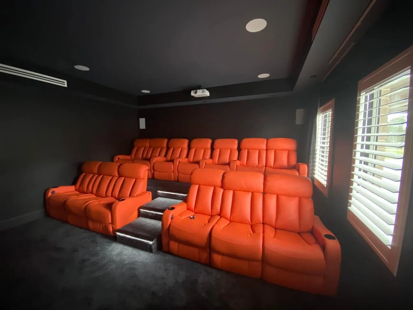 Two rows of orange leather recliners with lit steps between them