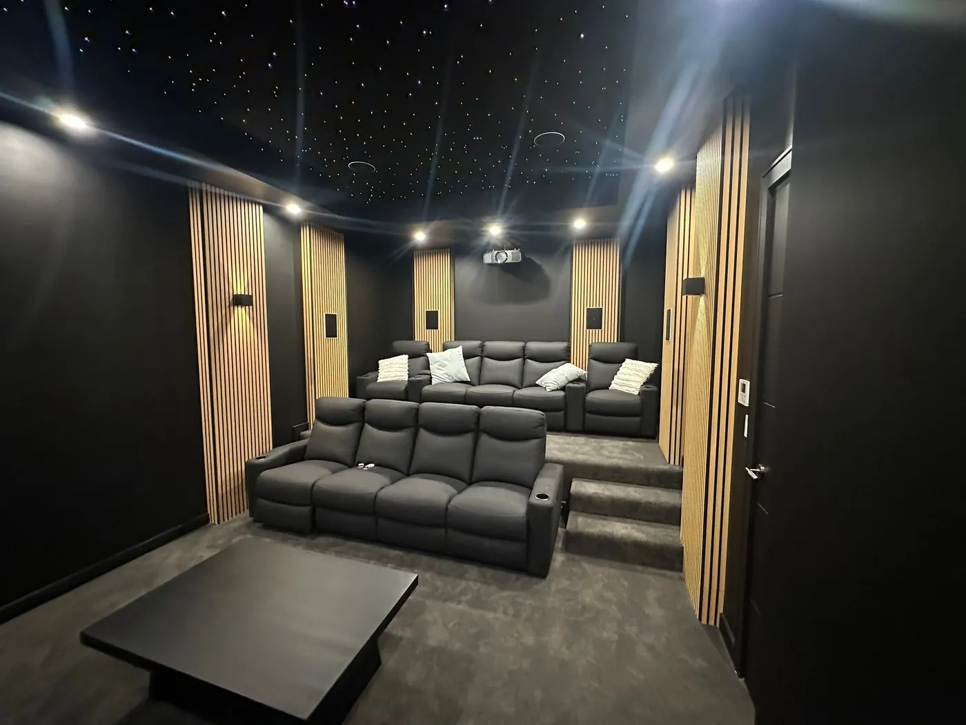 Two rows of leather recliners in a cinema room with timber slat panels
