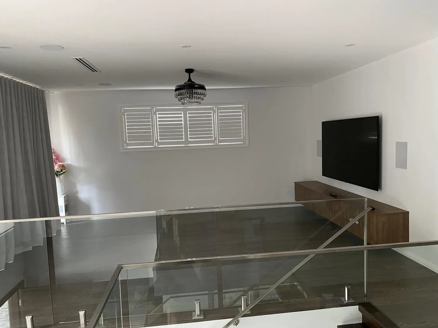 Living room with in-ceiling speakers and a wall-mounted TV, viewed from upstairs