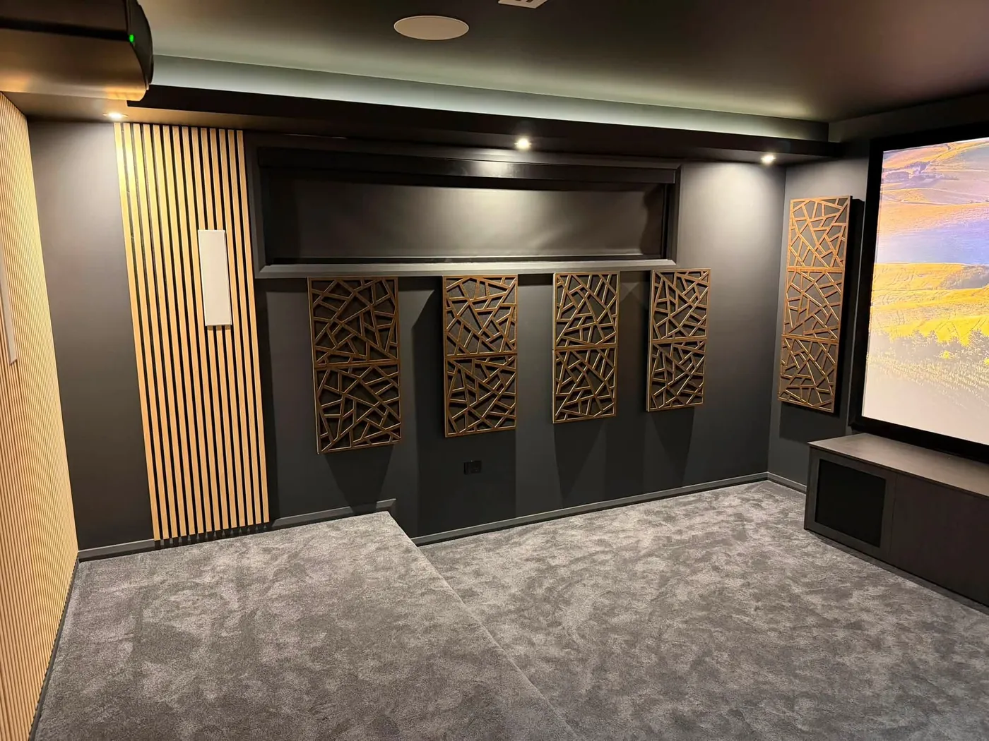 Patterned acoustic diffuser panels and timber slats on a cinema wall