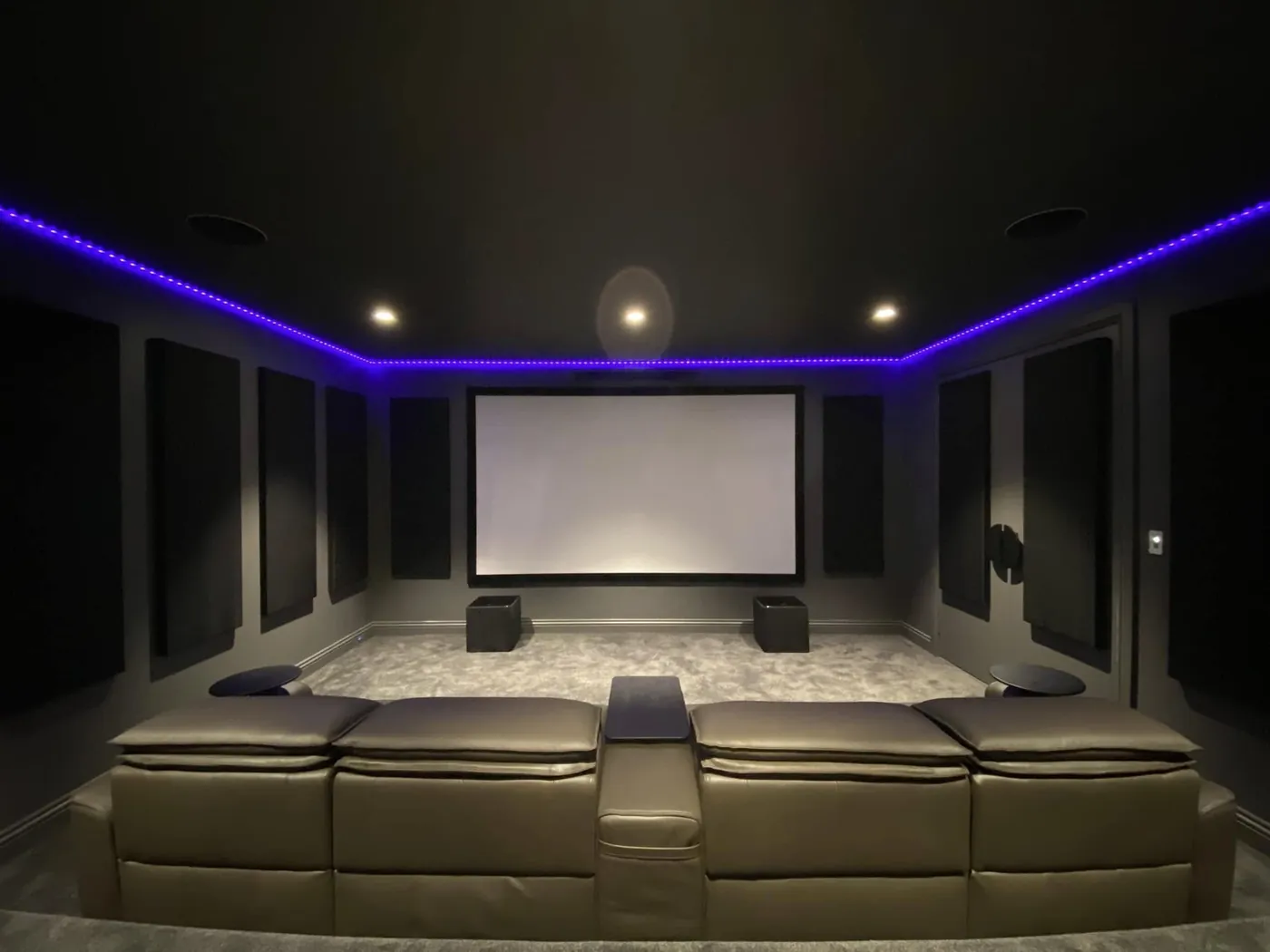 Cinema room lined with acoustic wall panels under purple LED lighting