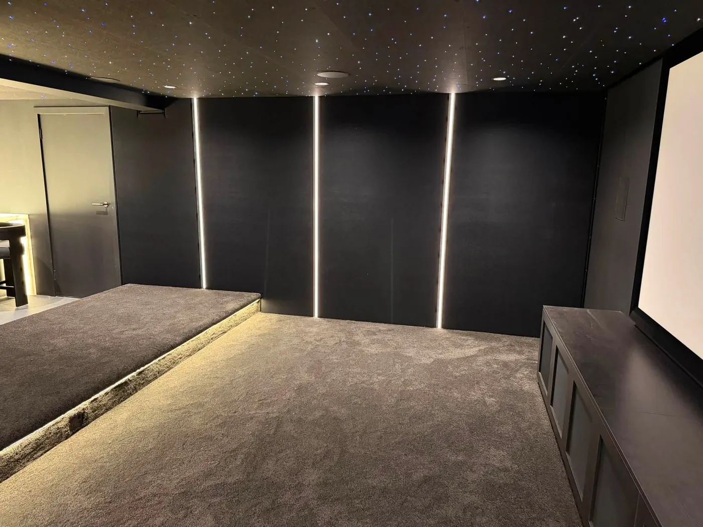 Lined cinema walls with vertical LED light strips and a carpeted riser