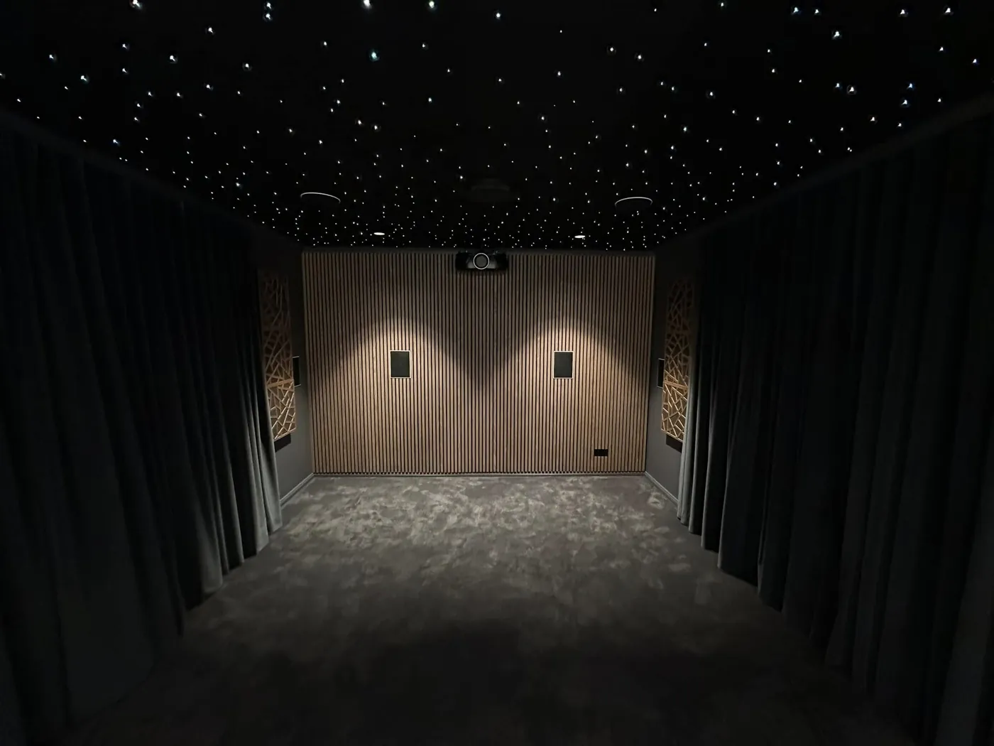 Star-light ceiling over a long cinema room with curtained walls