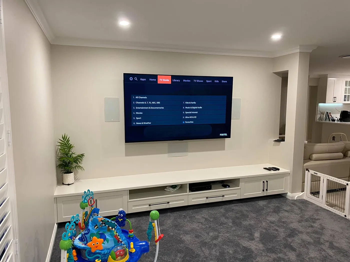 TV wall-mounted above a long white cabinet with in-wall speakers