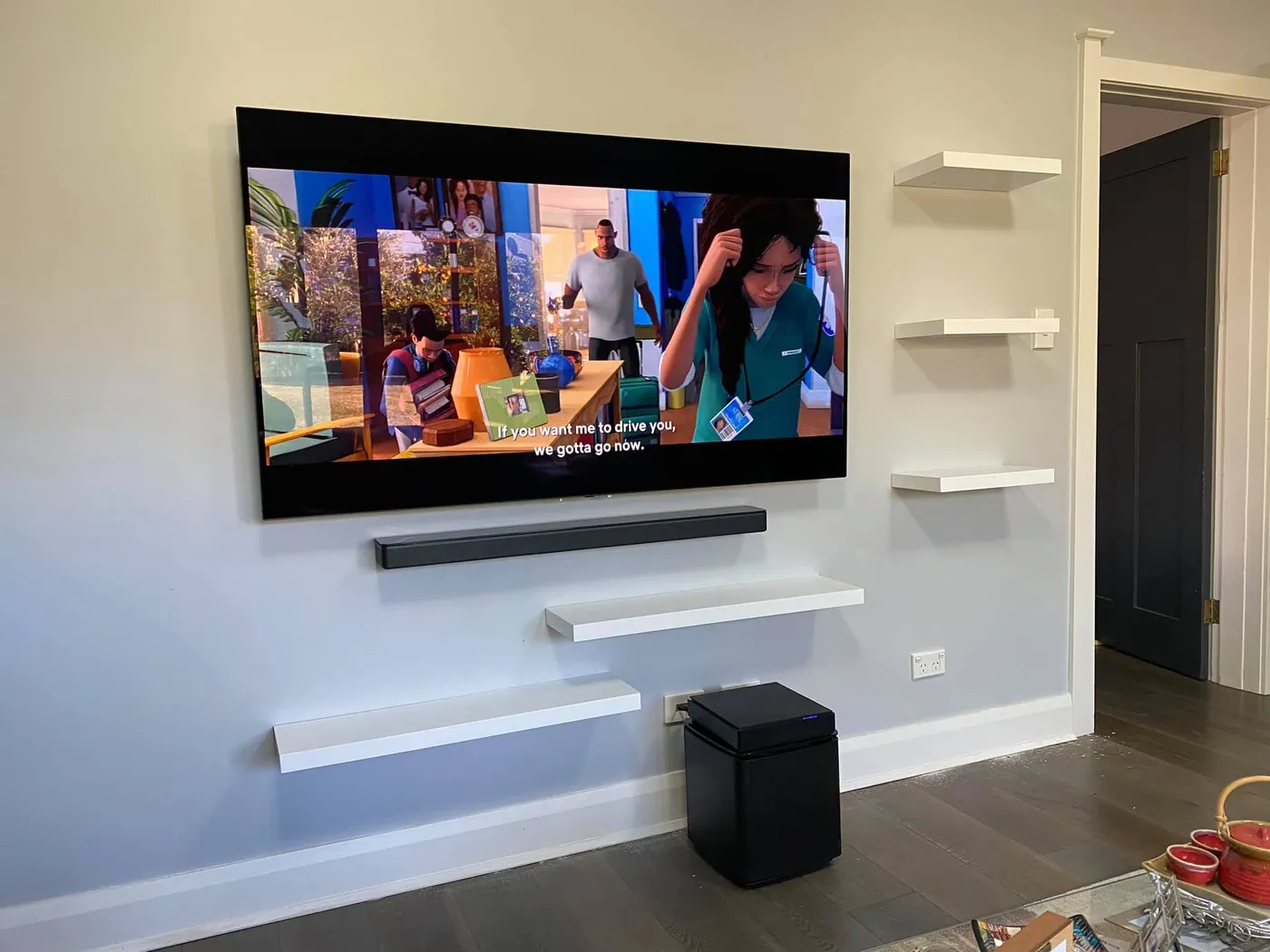 Wall-mounted TV with a soundbar and floating shelves