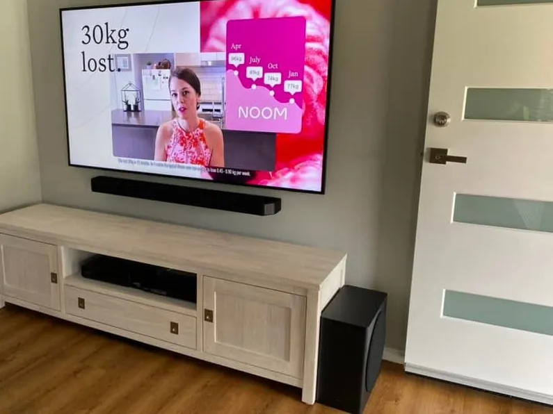 TV wall-mounted above a soundbar and cabinet in a living room